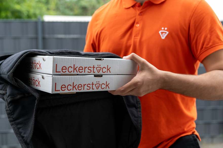 Leckerstück-Fahrer packt Liefertaschen ins Auto
